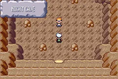 Captura del juego: el jugador dentro de una cueva de roca marrón y, arriba a la izquierda, el rótulo blanco de entrada de zona con el texto NIGHT CAVE